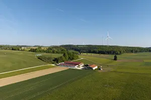 An expansive field landscape with a farm and wind turbines
