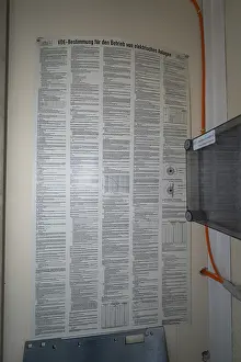 Category Historic EN Prints: An extensive poster with regulations for the operation of electrical systems is attached to a wall