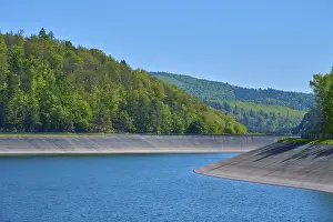 An extensive reservoir within a green hilly landscape under a clear sky