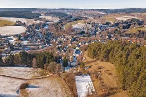 Extensive winter landscape with a village and surrounding fields under clear skies