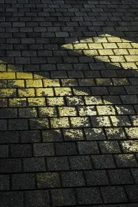 Faded yellow markings on dark, textured stone pavement create a striking contrast