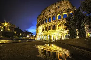 Famous Colosseum reflecting off the small rain puddle on mud