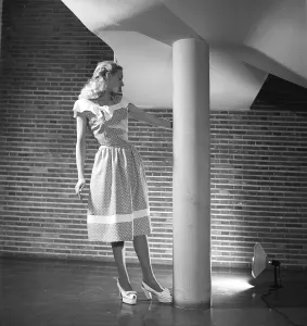 Fashion 1946, a young blonde female model dressed in the fashion of the year. Her sleeveless dress has a polka-dot pattern and is of a summery, lightweight type with a narrow waist and a length that reaches below the knees
