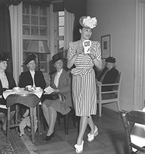 Fashion show 1946. A young dark-haired female model at a fashion show. She is wearing a period 1940s suit with matching striped skirt and waist-length jacket