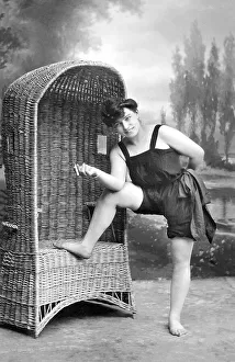 Fashion, swimwear, woman with cigarette and in bathing clothes standing in front of a beach chair
