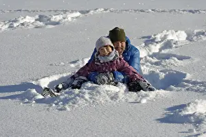 Father and daughter sitting in the deep snow