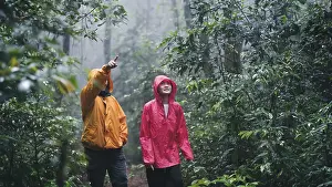 A father and daughter wearing raincoats hiking exploring a misty