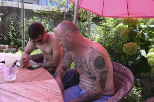 Father and son in the garden on a mobile phone under a red parasol