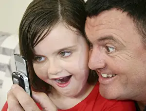 Father and young daughter play a game on her cell phone