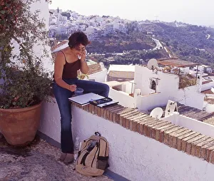 Female artist sits on a wall and draws in Frigiliana