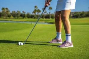 Female golfer concentrating intensely while hitting the golf ball on a bright