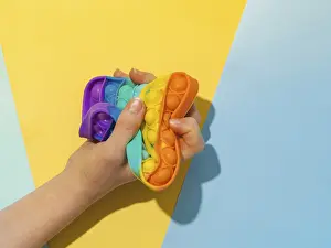 Female hand with popit toy clenched into fist