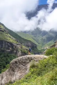 Female hiker standing in front of landscape with mountains and fog