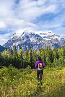 Female hiker walking through a meadow toward the majestic mount robson