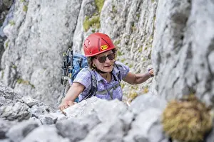 Female mountaineer with helmet climbing a rock face