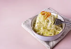 Fermented cabbage on a fork on a beige background