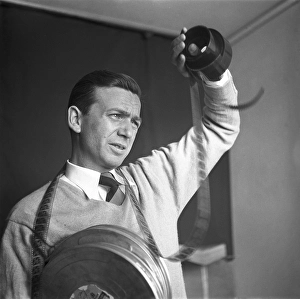 Film interest in the 1950s. A man holding a roll of film is looking at the frames to see what's on it