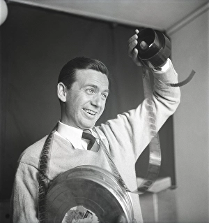 Film interest in the 1950s. A man holding a roll of film is looking at the frames to see what's on it