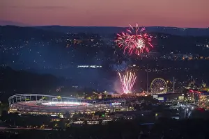 Fireworks at night illuminate the city above a stadium