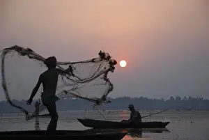 Category Historic EN Prints: Fisherman in boat throwing net in silhouette