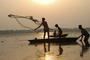 Category Historic EN Prints: Fishermen in boat throwing net in silhouette