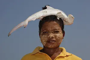 Fishwife carrying a small hammerhead shark on her head