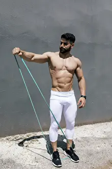 Fit man exercises with a green resistance band outdoors