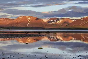 Fjord, low tide, stones, mountains reflected in the water