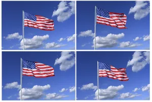 The flag of United States flutters in the wind in a blue sky with white clouds