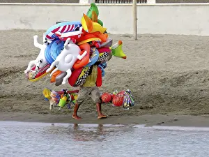 Flying merchant, seller overloaded with large quantities of beach toys