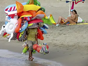 Flying merchant, seller overloaded with large quantities of beach toys