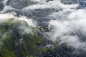 Fog, clouds moving around moss-covered mountains