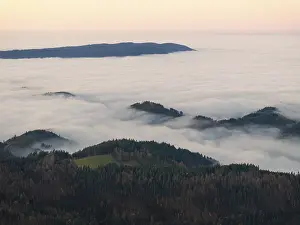 Fog slowly drifts over the wooded hills and mountains at dusk