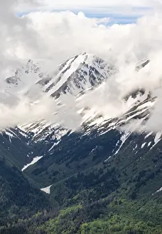Fog sweeps around mountain peaks with remnants of snow