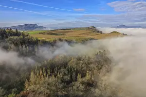 Foggy landscape in Hegau with hills and forests under a clear blue sky