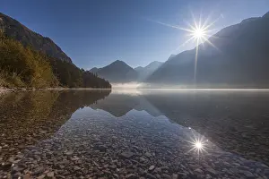 Foggy mood and reflection of mountains in mountain lake