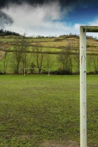A football field is set against rolling hills and trees