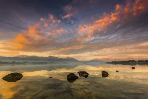 Forggensee with reflection of the cloudy sky and the Allgauer mountains in the background at sunrise