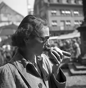 Frau eats bratwurst in bread roll on the market square