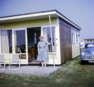 Frau steht in der Tuer eines Ferienhauses mit geparktem Morris Minor, privates Ferienanwesen in Miami Beach, Sutton on Sea, Lincolnshire, England, Grossbritannien, 1968