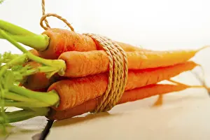 Fresh baby carrots bunch tied with rope on a rustic table