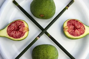 Fresh green figs with blades of horse tail on a plate