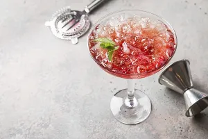 Fresh red margarita cocktail with ice and mint over gray background