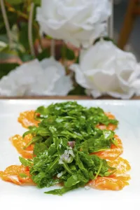 Fresh salmon carpaccio sushi sashimi with arugula rocket salad and caper on top