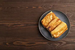 Fried crispy pancakes with meat and cheese on brown wooden background