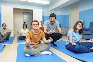 Friendly male yoga instructor directing a class with people with special needs and down syndrome