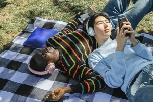 Two friends enjoy a sunny day, lying on a checkered blanket