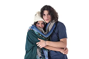 Two friends are hugging each other like they are cold while wearing the same scarf