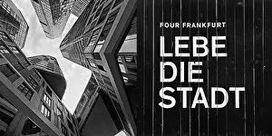 Frog's-eye view of skyscrapers in the banking district and construction fence with the inscription Lebe die Stadt