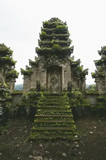 Frontal view of an ancient temple ruin with moss-covered stairs
